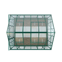 A rectangular Rhino Greenhouse with a green metal frame and glass panels. It stands on a gravel surface with larger stone slabs arranged in a path inside.