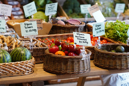 A selection of organic fruit and veg in wicker baskets on a wooden table