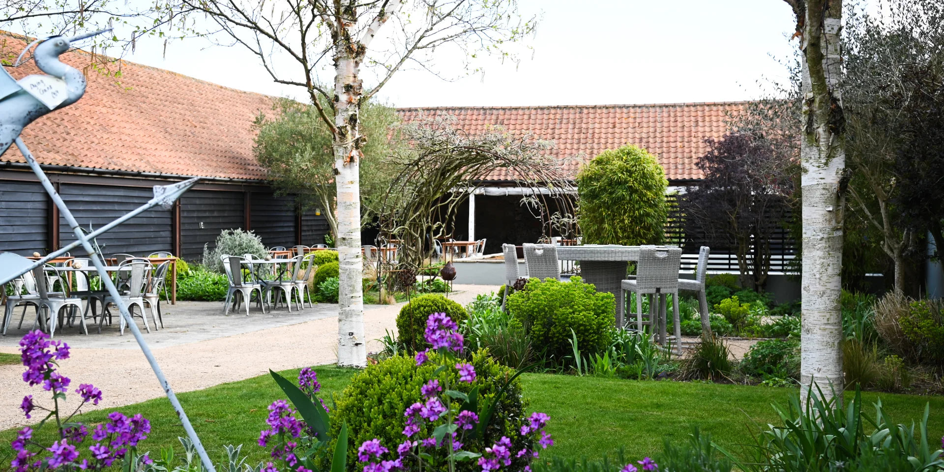 A converted outbuilding in a landcaped courtyard with tables and chairs