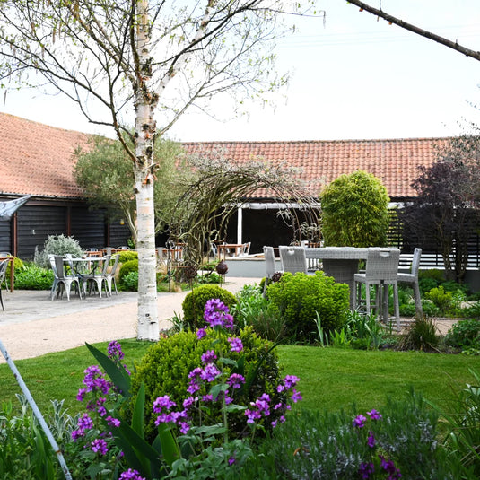A converted outbuilding in a landcaped courtyard with tables and chairs