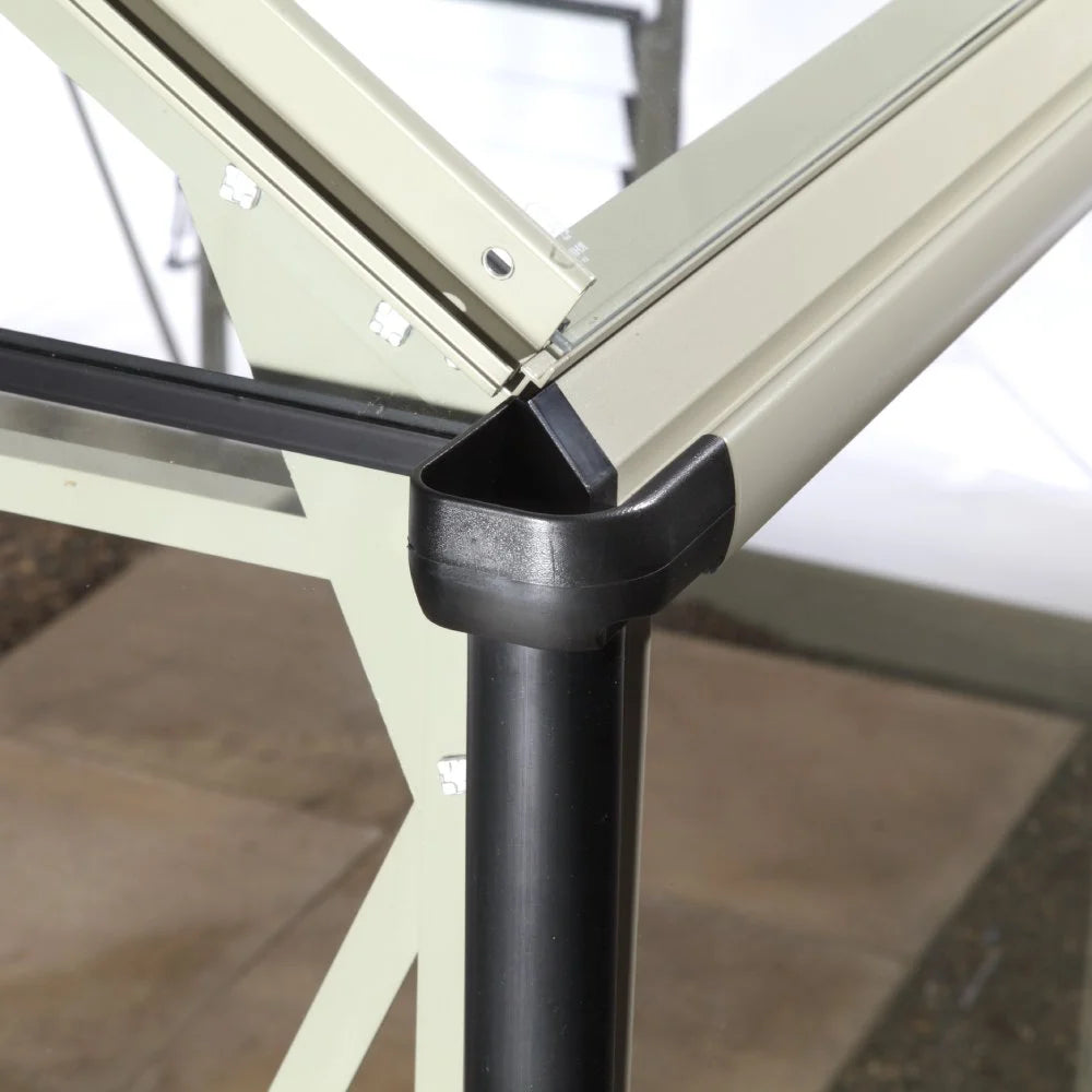 A Rhino Greenhouse corner structure featuring sturdy metal framing and black corner protectors, set against a tiled garden floor and surrounded by garden tools, illustrating robust construction elements.