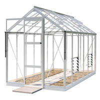A small, transparent Rhino Greenhouse with a metal frame stands empty on concrete, featuring a sliding door and an interior with a gravel path, set against a plain white background.