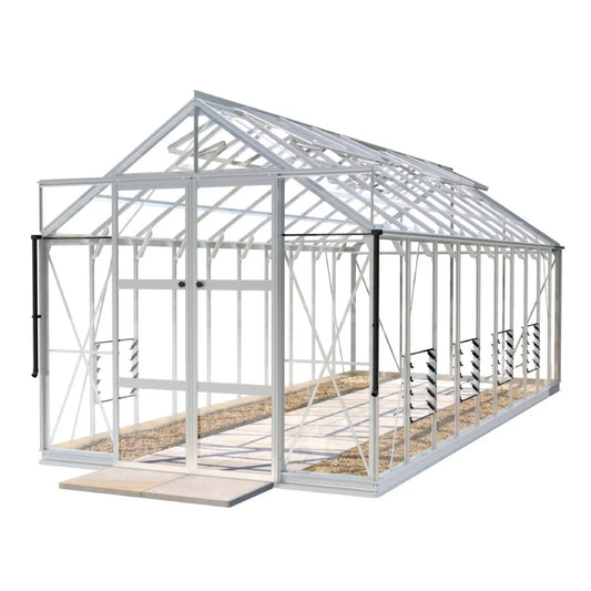 A large glass-paneled Rhino Greenhouse with a triangular roof has sliding doors and sturdy metal frames, standing on a paved ground. Inside, soil beds line the side pathways.