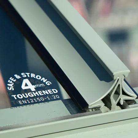 A section of Rhino Greenhouse glass sits securely embedded in a sturdy frame; text reads SAFE & STRONG 4mm TOUGHENED EN12150-1:20 against a blurry outdoor background.