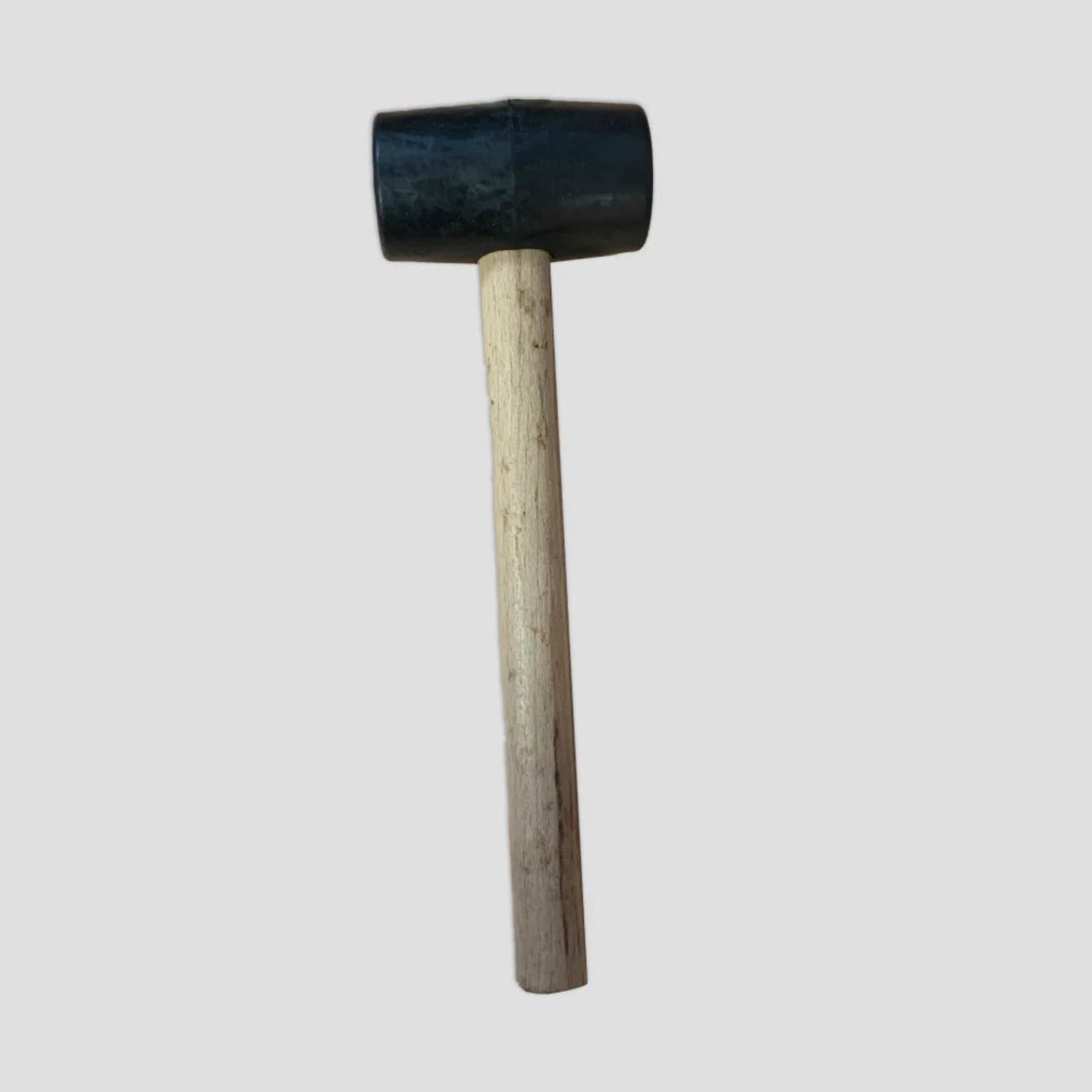 A rubber mallet with a wooden handle is positioned upright against a plain white background, showcasing its simple design.