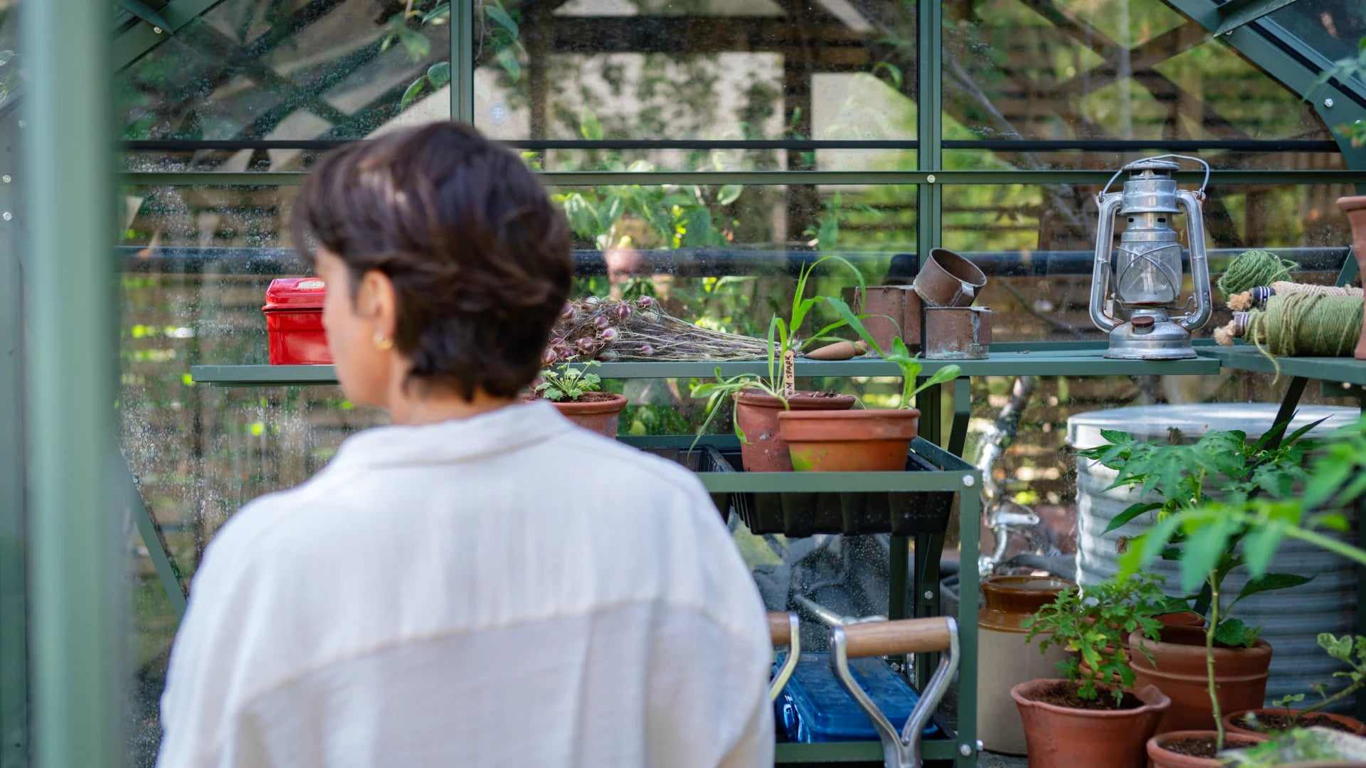 Miria working inside her greenhouse surrounded by seedlings and plants in terracota pots