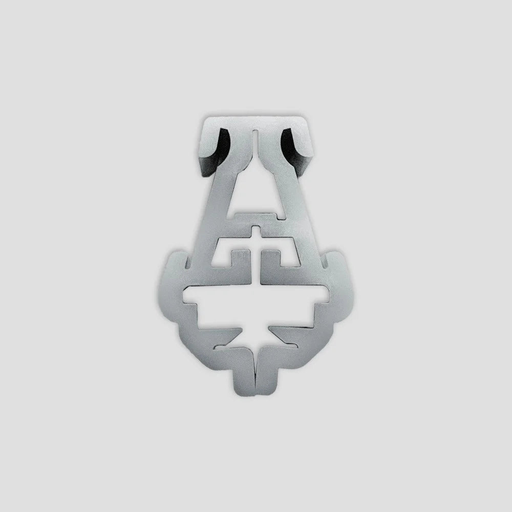 A metal Rhino Greenhouse glazing clip rests on a plain, light gray background. The clip features symmetrical, intricate cutouts designed to securely hold glass panels in place.