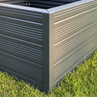 Metal planter box with horizontal grooves stands on grass, showcasing a sturdy, modern design suitable for gardening.